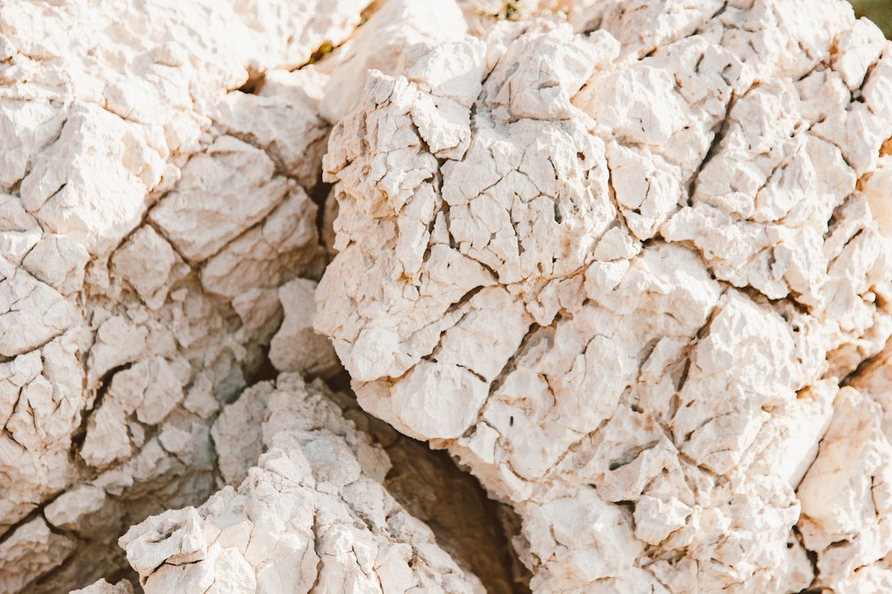 A close-up of textured white rocks with natural cracks, captured outdoors in bright sunlight.
